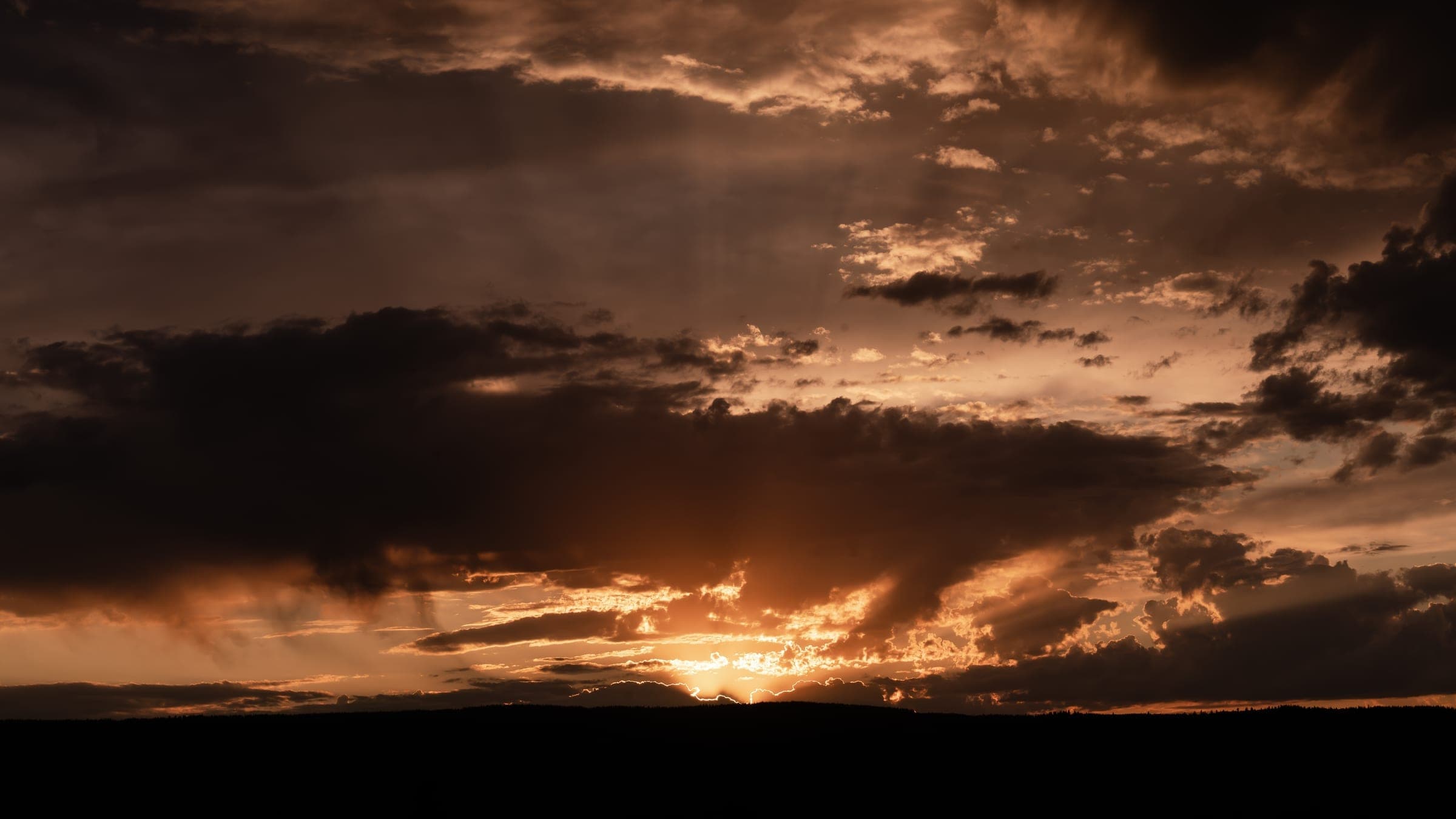 Silhouetted mountains against a burning sunset sky